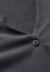 Dunkelgrauer Stoff mit glatter Textur, mit einem geschwungenen Ausschnitt und einem einzelnen schwarzen Knopfdetail. Einfaches und minimalistisches Design.