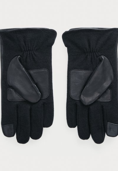 Svarte hansker laget av ull med lærdetaljer. Har teksturert overflate, rynket håndledd og forsterkede håndflateputer.