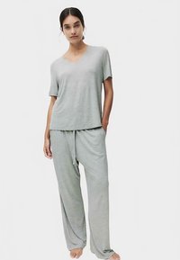 Ensemble de vêtements d'intérieur gris clair comprenant un haut à manches courtes avec col en V et un pantalon à cordon de serrage ; texture douce, coupe décontractée, silhouette fluide.