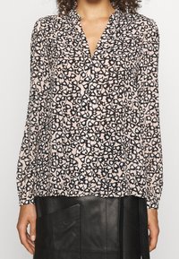 Langärmlige Bluse in Hellrosa mit einem schwarzem und weißen Leopardenmuster, ausgestattet mit einem V-Ausschnitt und Raffung an den Schultern.