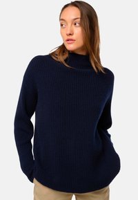 Pull en maille côtelée bleu marine avec un col montant et des manches longues, présentant une coupe décontractée et une texture douce, adapté à un usage décontracté.