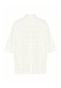 White oversized shirt with a textured grid pattern, short sleeves, a collar, and a relaxed fit, featuring a central seam down the back.
