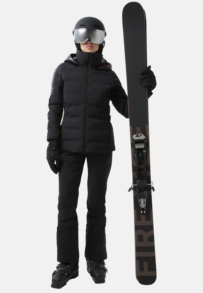 Black insulated jacket with a high collar, black ski pants, and gloves. Holding a black snowboard with red accents and bindings. Gray helmet and goggles.