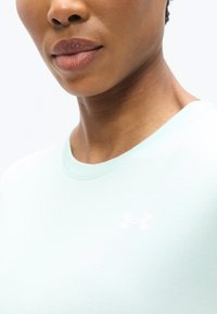 Αθλητική μπλούζα σε ανοιχτό μέντα πράσινο χρώμα με στρογγυλή λαιμόκοψη και κοντά μανίκια, με ένα μικρό λευκό λογότυπο της Under Armour στο στήθος.