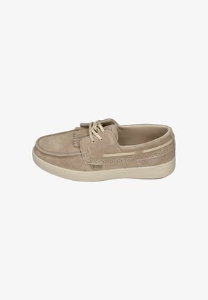 Mocasín casual de ante beige con cordones delanteros, detalle de flecos y suela de goma blanca sobre fondo blanco.