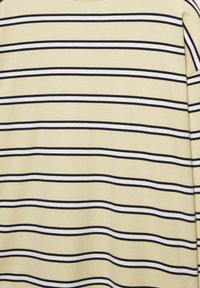 Tessuto beige con sottili strisce orizzontali nere e bianche uniformemente distanziate, che mostra una texture liscia e leggere pieghe.