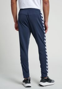 Navy athletic pants with a slim fit, featuring a black and white chevron pattern along the side and a smooth, lightweight fabric.