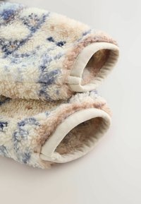 Blød fleecejakke med ærmer i beige kant, der har et mix af creme, blå og lysebrune abstrakte mønstre.