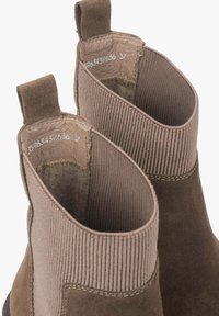 Para brązowych zamszowych butów Chelsea z prążkowanymi elastycznymi panelami bocznymi, pętelkami do ściągania oraz wnętrzem wyściełanym polarem, widzianych z góry.