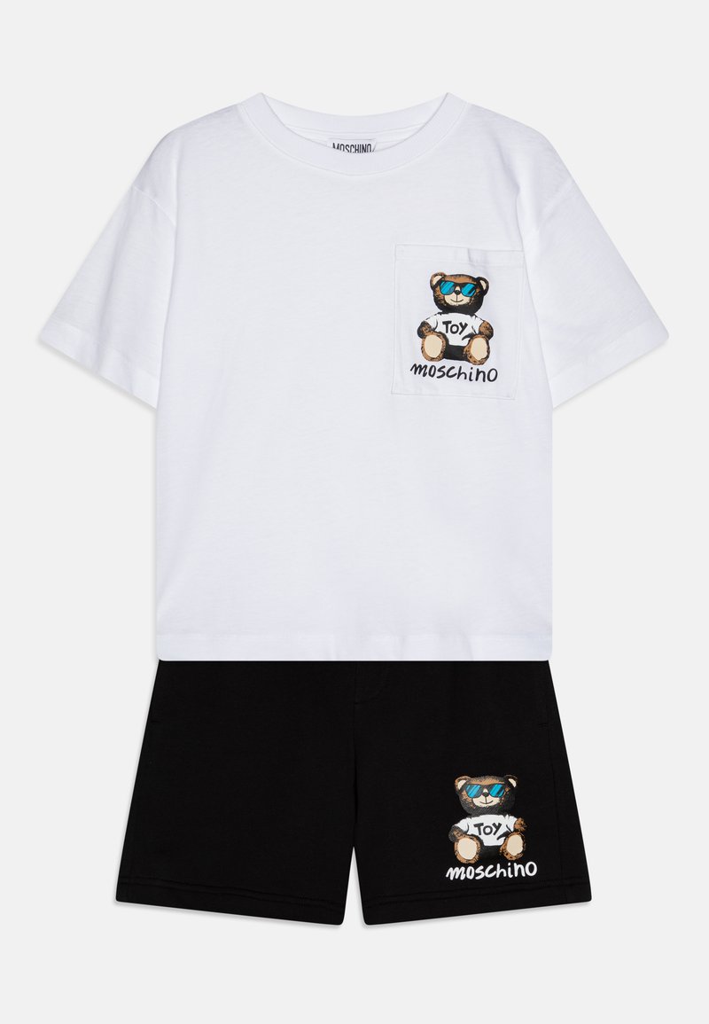 Camiseta blanca de algodón con un bolsillo que presenta un gráfico de un oso de peluche. Pantalones cortos negros con bordado de oso de peluche a juego. Conjunto casual de dos piezas.