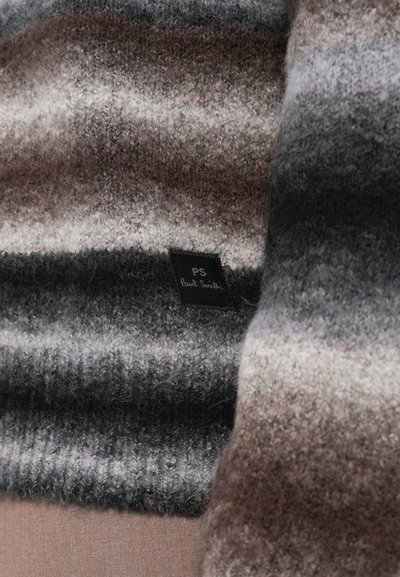 Triibuline sall halli, pruuni ja valge toonides, valmistatud pehmest villast. Sellel on väike must silt kirjaga "PS Paul Smith".