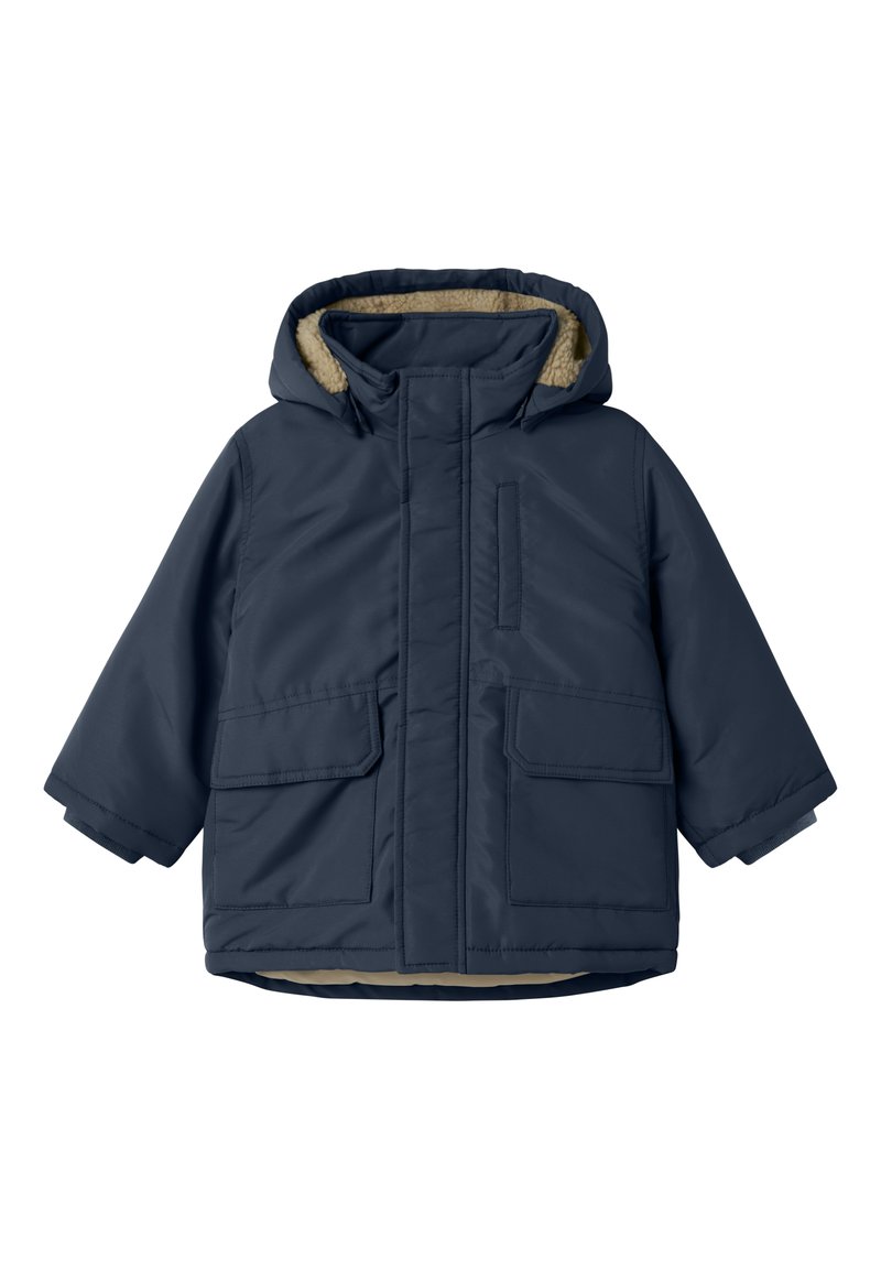 Giacca trapuntata blu navy con cappuccio foderato in pelliccia, due tasche frontali e chiusura con zip. Texture liscia con finitura opaca.
