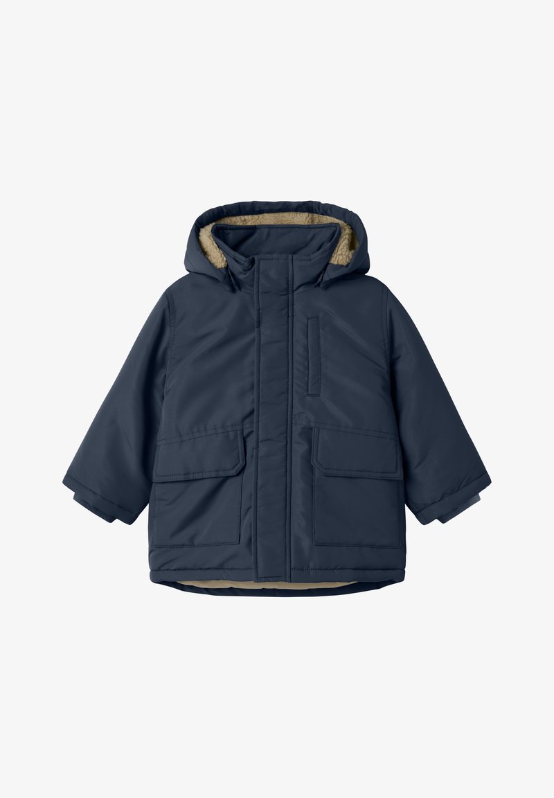 Giacca trapuntata blu navy con cappuccio foderato in pelliccia, due tasche frontali e chiusura con zip. Texture liscia con finitura opaca.