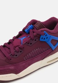 Burgunderfargede sneakers laget av semsket skinn og lær, med blå detaljer, mesh-paneler og teksturerte elementer. Tykk snøring og gummisåle.