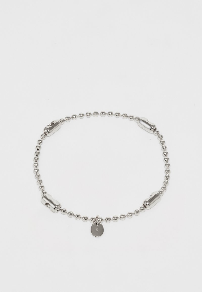 Suda bumbu ķēdīte ar pulētām akcentiem un mazu apaļu piekariņu. Iezīmē gludu tekstūru un vienkāršu, noapaļotu dizainu.