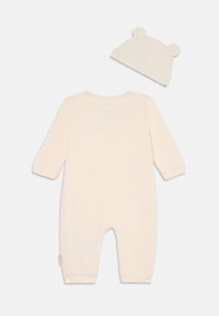 Kremfarget baby romper med lange ermer, ribbestrikket tekstur og rund hals, sammen med en matchende hatt som har bjørneører.