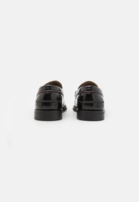 Chaussures noires en cuir avec une finition brillante, bout rond, petit talon et détails de couture sur les côtés. Design minimaliste, sans embellissements.