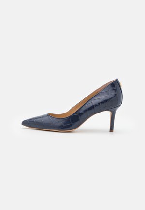 Chaussure à talon haut bleu marine à bout pointu avec texture crocodile et talon fin de hauteur moyenne sur fond blanc uni.