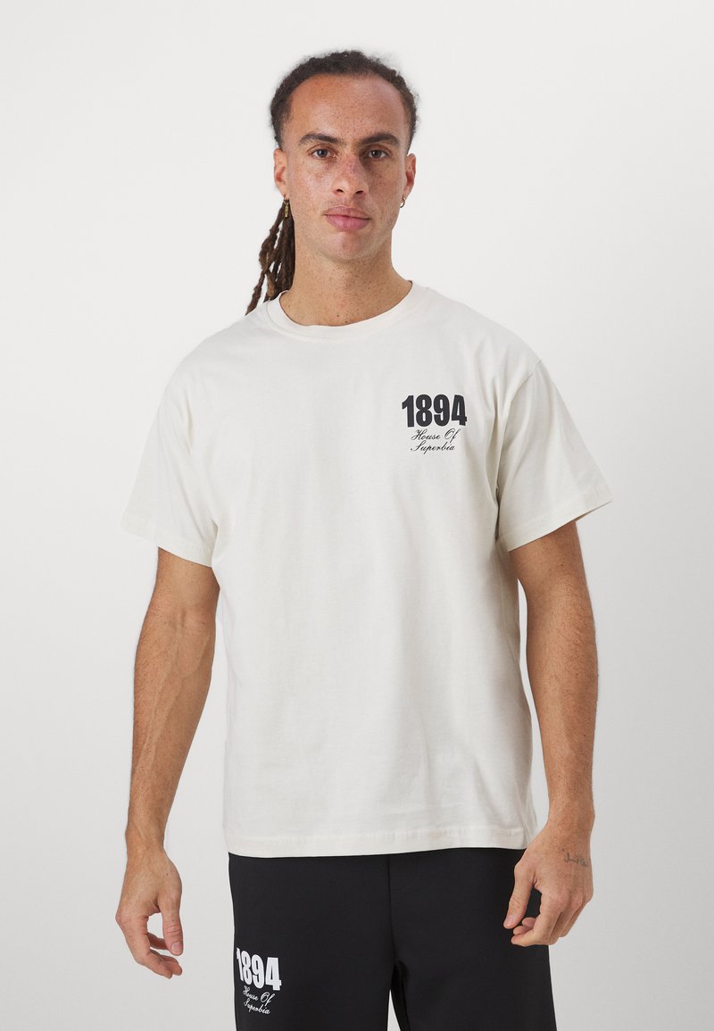 White cotton t-shirt with short sleeves, featuring a black printed design on the left chest area and a relaxed fit. Simple and classic style.