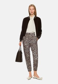 Black bomber jacket with white accents, white blouse, leopard print trousers, white flat shoes, and a black leather bag.