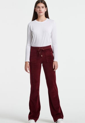 Bordeaux veloursbroek met een losse pasvorm, voorzien van een trekkoord in de taille, twee voorzakken en een zachte, gestructureerde afwerking.