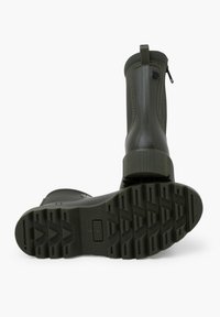 Bottes en caoutchouc vertes jusqu'à la cheville avec une semelle texturée, une fermeture éclair à l'arrière et des coutures renforcées sur les côtés pour la durabilité et le confort d'utilisation.