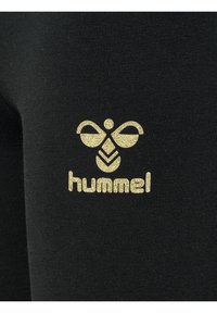 Zwarte stof met een gouden logo met een gestileerde bij en het woord "hummel" eronder. De textuur is glad en aansluitend.