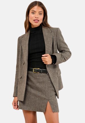 Brown herringbone blazer with two buttons and a notched lapel, paired with a black ribbed turtleneck and a matching pencil skirt.