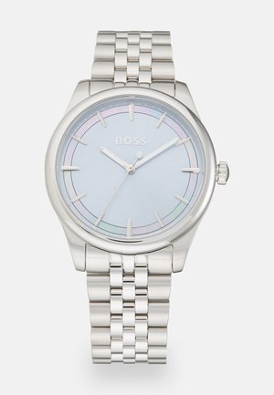 Montre en acier inoxydable argenté avec un cadran bleu clair, présentant de fines aiguilles argentées, un sous-cadran simple et un bracelet en métal poli.