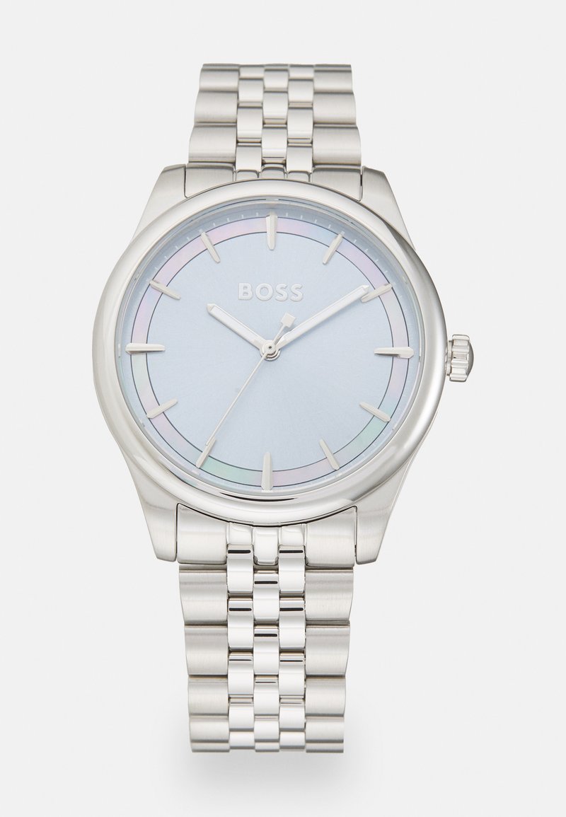 Hõbedane roostevabast terasest kell heleda sinise dialiga, millel on õhukesed hõbedased käed, lihtne aldial, ja poleeritud metallist rihm.