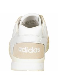 Vit och beige Adidas-sneaker sedd bakifrån som visar varumärket på hälfliken och vadderad ankelskåra.