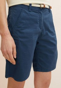 Granatowe szorty wykonane z lekkiego materiału o gładkiej fakturze, z bocznymi kieszeniami oraz plecionym białym paskiem z brązową klamrą.