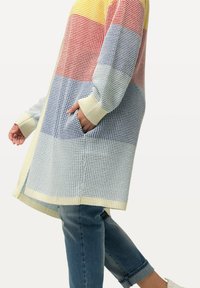Cardigan lavorato a maglia colorato e testurizzato, con strisce gialle, rosse, blu e crema. Presenta tasche e polsini a coste, raggiungendo la metà della coscia.