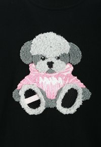 Un tejido negro presenta un diseño bordado texturizado de un perro de peluche con un suéter rosa con acentos grises y patas redondeadas negras.