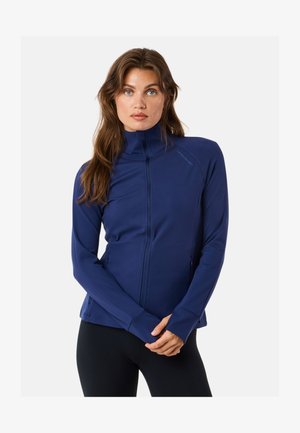 Tummansininen vetoketjullinen takki, jossa on korkea kaulus, pitkät hihat ja sivutaskut; valmistettu sileästä, joustavasta materiaalista, joka on muotoiltu istuvaksi.