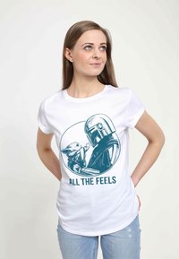 Hvid bomulds t-shirt med et cirkulært grafisk design af en figur og en hjelm, med teksten "ALL THE FEELS" i teal.
