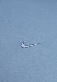 Light blue fabric with a small, stitched white Nike swoosh logo centered on the surface.