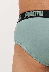 Lys grønne bomullsboxer med svart elastisk linning som har "PUMA"-logoen i en kontrasterende lys grønn farge. Myk tekstur og tettsittende design.
