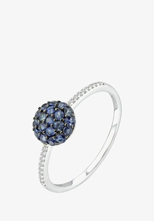 Anillo racimo de zafiros con una piedra preciosa azul circular en el centro, montado en plata. Acentuado con pequeñas piedras transparentes a lo largo de la banda.