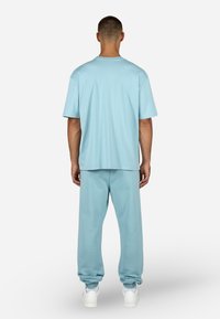 Σετ από ελαφρώς μπλε, άνετη μπλούζα T-shirt και φόρμες, κατασκευασμένο από απαλό ύφασμα, με στρογγυλή λαιμόκοψη και ελαστικές μανσέτες στα παντελόνια.