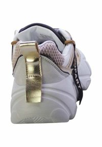 La sneaker presenta una toma superiore in tessuto bianco con un tassello in oro texturizzato sul tallone, fodera in rete e branding nero sul retro. Suola spessa bianca con scanalature.