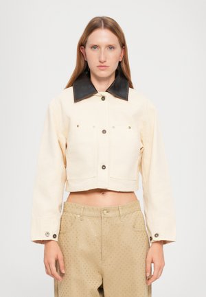 Cropped beige jacket with a black leather collar, button-front closure, and two front pockets. Smooth fabric with minimal detailing.