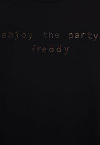 T-shirt nera con scollatura rotonda che presenta la scritta "enjoy the party freddy" composta da piccoli chiodini metallici lucidi di vari colori.