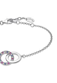 Bracelet en argent comportant deux anneaux entrelacés ; l'un avec une finition lisse, l'autre orné de pierres roses, bleues et transparentes.