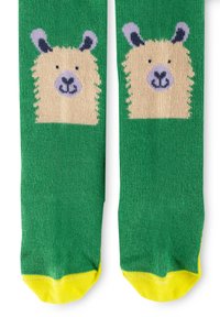 Grüne Socken mit plüschiger Textur haben ein beiges Tiergesicht-Design an der Oberseite, akzentuiert mit lila Ohren und gelben Spitzen.