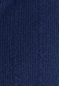 Tessuto a maglia di un profondo blu navy, con un motivo a coste testurizzato. Il materiale appare morbido e leggermente peloso, con fibre visibili.