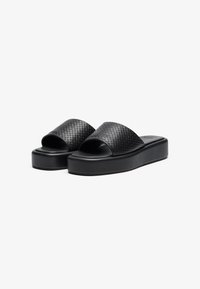 Black platform sandals with a woven texture on the straps, open-toe design, and a thick, solid base for added height.