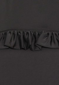 Tissu noir avec un détail froncé horizontal cousu au milieu, montrant la texture et les coutures.