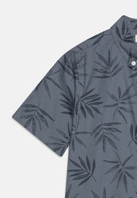 Grijs shirt met korte mouwen, voorzien van een herhalend zwart bladerenpatroon, een geknoopte kraag en contrasterende stiksels langs de naden.