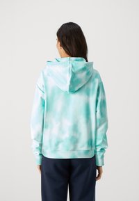 Hoodie tie-dye azzurro chiaro con cappuccio regolabile, tessuto morbido e polsini a costine. Presenta una vestibilità ampia e rilassata, senza dettagli frontali.